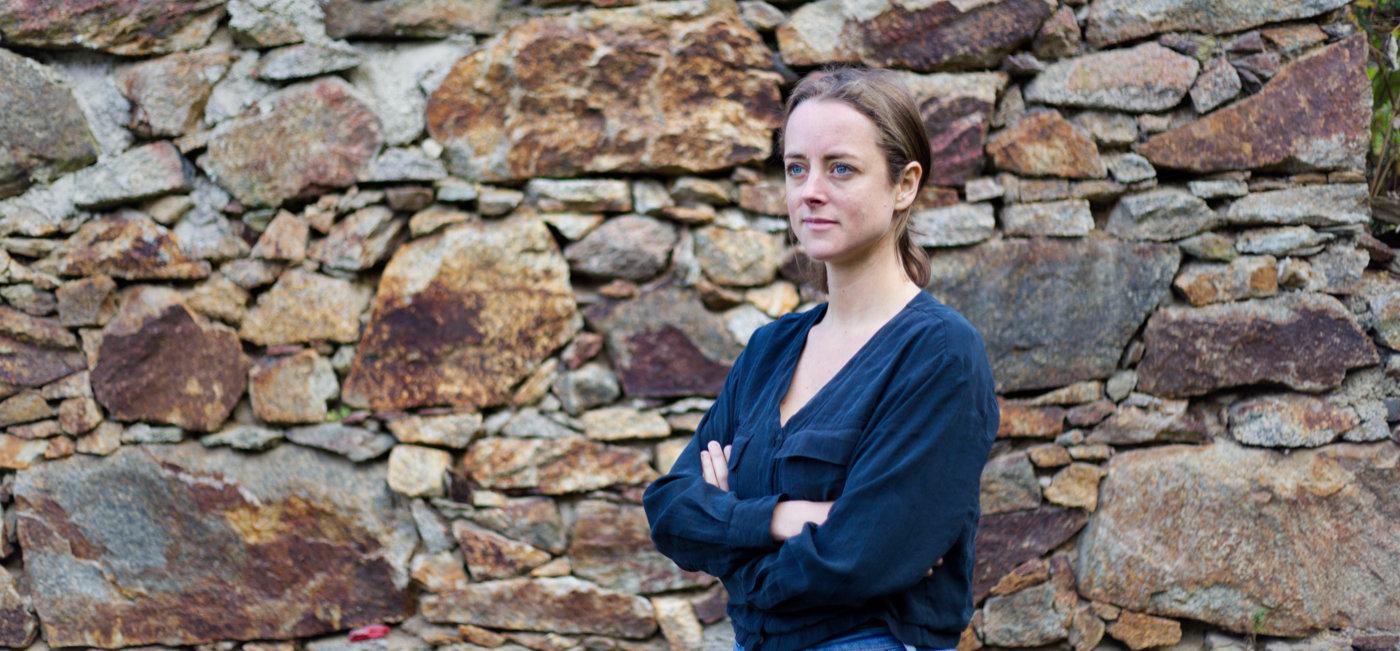 Rebecca Hughes | English Training and Language Services | Rebecca standing in front of an old stone wall